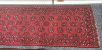 Modern Eastern-style red ground runner with elephant foot gul decoration, in blacks, reds and