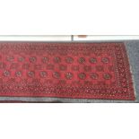 Modern Eastern-style red ground runner with elephant foot gul decoration, in blacks, reds and