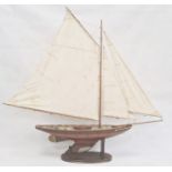 Varnished wood model yacht with canvas sails and metal fittings and the associated wooden stand,