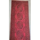 Long Eastern-style modern red ground runner with central repeating pattern, in reds and blacks,