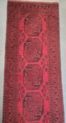 Long Eastern-style modern red ground runner with central repeating pattern, in reds and blacks,