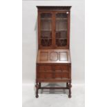 20th century oak bureau bookcase, the moulded pediment above two astragal glazed doors enclosing