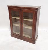 Walnut display cabinet with rectangular top, two glazed doors enclosing shelves, on plinth base,