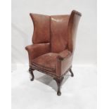 Possibly early 20th century wing back chair stamped Gregory and co in light brown leather with brass