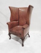 Possibly early 20th century wing back chair stamped Gregory and co in light brown leather with brass