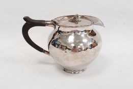 Silver covered jug by A E Jones, London 1911 of circular form with hammered finish, the hinged cover