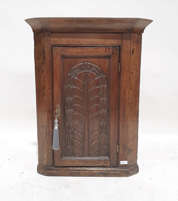 19th century oak wall-hanging corner cupboard, the single door with carved decoration enclosing