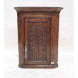 19th century oak wall-hanging corner cupboard, the single door with carved decoration enclosing