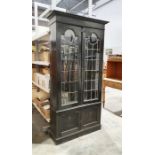 Early 20th century ebonised display cabinet, the leaded glazed doors enclosing shelves, two cupboard