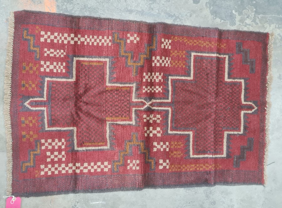 Eastern rug, red ground with two central medallions in reds, blacks, oranges and creams, 130 x 85cm