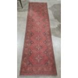 Modern Eastern-style red ground runner with repeating motif to central field, stepped border,
