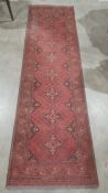 Modern Eastern-style red ground runner with repeating motif to central field, stepped border,