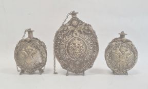 Three silver coloured metal gunpowder flasks, possibly Russian, all relief decorated, two