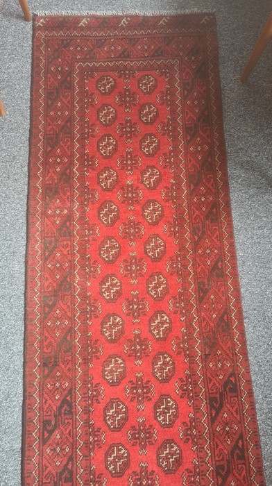 Modern Eastern-style red ground runner with elephant foot guls to the central field, in reds, blacks