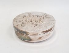 A 20th century silver coloured metal circular box, the lid relief decorated with figures in a