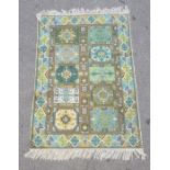 Modern green ground rug, the central field with ten panels in blues, greens and yellows, 120cm x