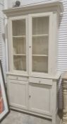 Grey painted bookcase cabinet with moulded cornice above two glazed doors enclosing shelves, two