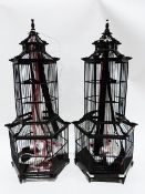 Two black painted wooden decorative pagodas/birdcages of hexagonal tier design hung with ribbons (