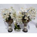 Two large silver coloured metal and glass vases with faux orchids displayed, and a glass bowl of