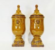Pair of modern treacle glazed ceramic urn-shaped lidded vases with applied lion decoration (2)
