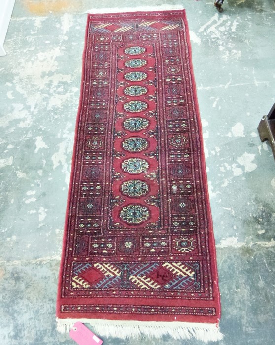 Eastern style red ground rug with ten elephant foot gul pattern in centre, with geometric border and