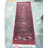 Eastern style red ground rug with ten elephant foot gul pattern in centre, with geometric border and