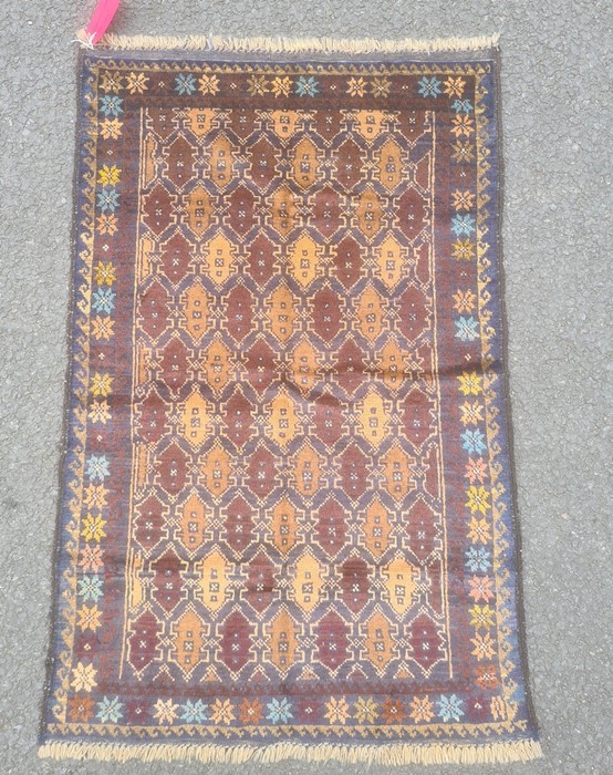 Baluchi rug, the central field decorated with brown lozenges within blue borders and within a floral