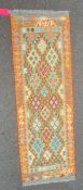 Chobi kilim runner with lozenges of green and blue on an orange ground, 200cm x 66cm.