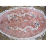 Chinese wool rug, oval, pink ground decorated with dragons