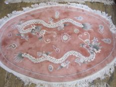 Chinese wool rug, oval, pink ground decorated with dragons