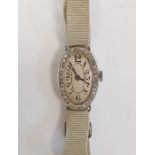 A 1920s platinum and diamond lady's wristwatch on fabric strap, oval with Arabic numerals and an