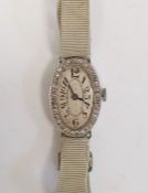 A 1920s platinum and diamond lady's wristwatch on fabric strap, oval with Arabic numerals and an