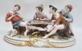 Ciche porcelain figural group of boys seated at a table playing cards, the oval base with gilt