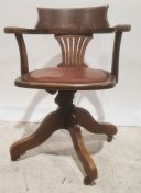 Oak office swivel chair with brown leather seat, the whole raised on castors