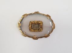 Victorian moonstone and gold-coloured metal mourning brooch, the oval stone bevelled and set with