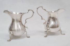 Two similar silver milk jugs with scroll handles, on shaped pad feet, one Birmingham 1959, the other