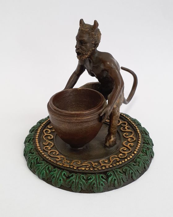 Bronze model of a faun holding a large vase, on a circular base, gilt and green painted, with