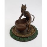 Bronze model of a faun holding a large vase, on a circular base, gilt and green painted, with