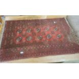 Red ground Eastern-style rug, the central field with ten elephant foot guls, stepped border, 117cm x