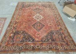 Red ground Eastern rug with three diamond-shaped medallions to the central field, decorated with