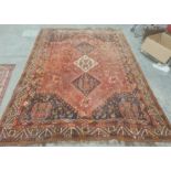Red ground Eastern rug with three diamond-shaped medallions to the central field, decorated with