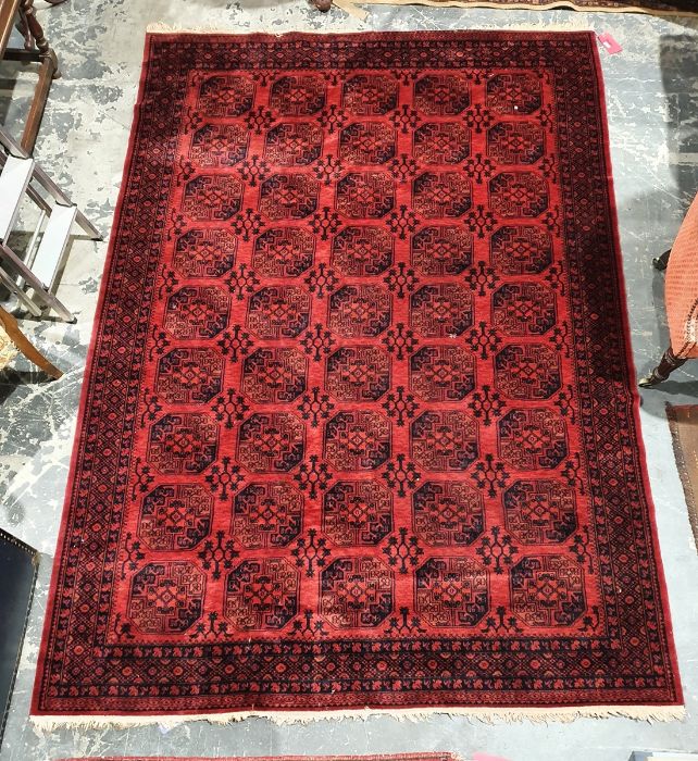 Modern Eastern-style red ground rug, the central field with elephant foot guls, stepped border