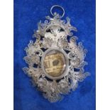 Victorian silver filigree reliquary pendant with central oval glass enclosing writing on paper
