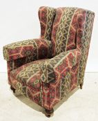 Victorian wing back armchair in red and green patterned upholstery, turned front feet to brown china