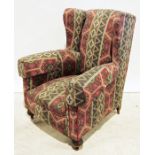 Victorian wing back armchair in red and green patterned upholstery, turned front feet to brown china