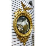 19th century circular wall mirror surmounted by eagle, with a carved giltwood frame, the convex