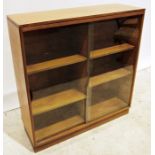 Mid-century modern teak bookcase with shaped sliding glass doors enclosing adjustable shelving, on