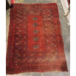 Red ground Eastern rug with five elephant's foot guls to the central field, stepped border, 110cm