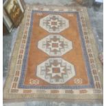 Eastern style rug with terracotta ground, central field with three repeating cream ground hooked