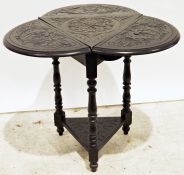 Dark stained triangular side table with drop-leaves, the whole with carved decoration, on turned and
